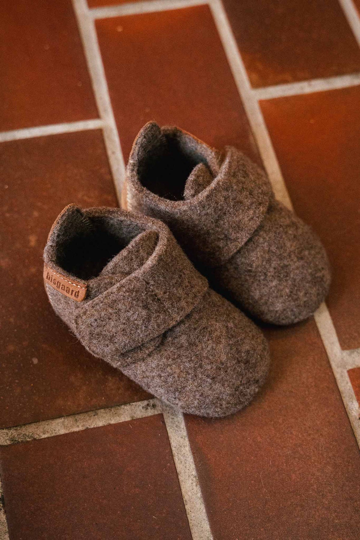 Baby Wool Camel – Wool baby booties – Bisgaard: two booties on a tiled floor.