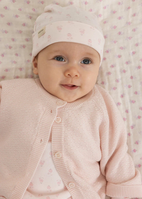 Pyjama avec pieds – Rubetta Mini Bloom – MarMar Copenhagen : bébé portant le bonnet rose clair dans un panier à langer.
