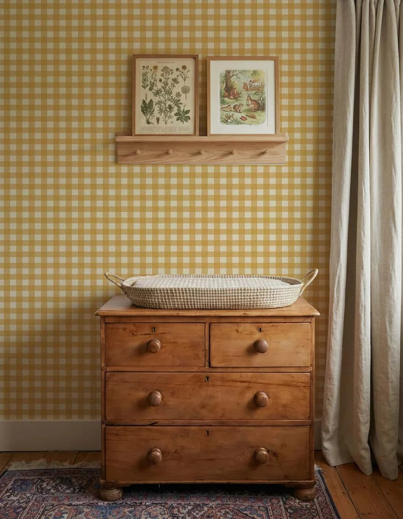 Papier peint Vichy jaune ocre d'Atelier Chien derrière une commode en bois avec panier à langer.