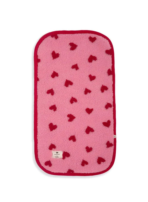 Alwero x Salty Stitch – Bassinet / Stroller Pad – 100% Merino Wool: flat lay of pink wool stroller liner with red hearts.