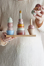 Celebrate Activity Toy – Bloomingville MINI: detail van een hand die een onderdeel op een stapel zet.