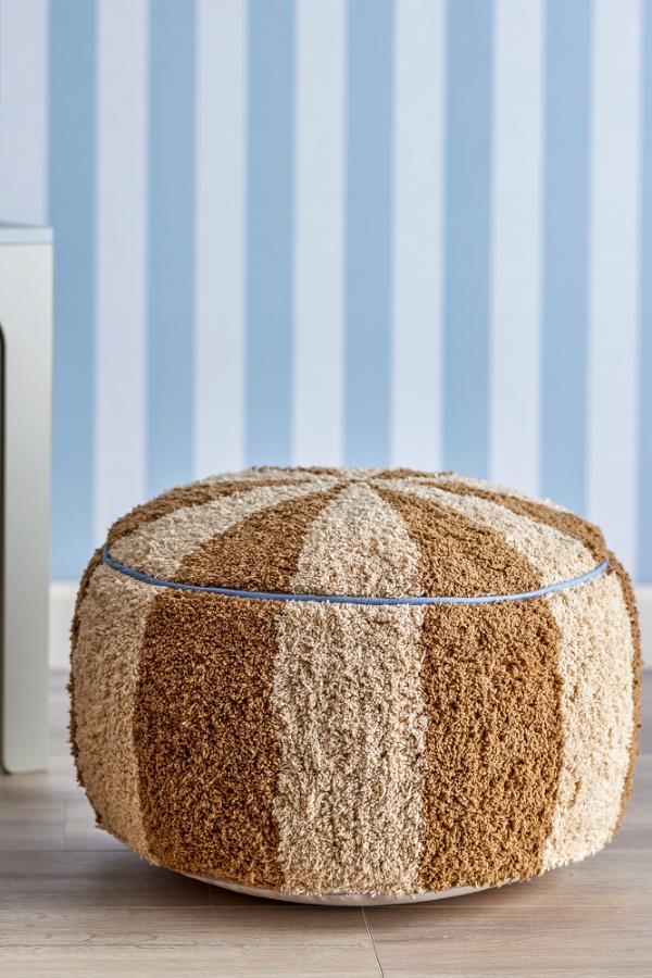 Charoline Pouf Brown – Bloomingville MINI: pouf in front of a wall with blue striped wallpaper.