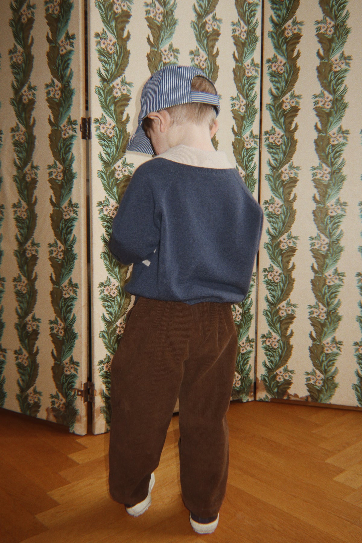 Wollen polo Basi – Dark Blue Stripe – Konges Sløjd: kind met blauwe polo en bruine broek, van achteren.