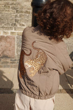 Thermojacke Juno Bomber – Walnut – Konges Sløjd: Detail der Leoparden-Illustration auf der Rückseite der getragenen Bomberjacke.