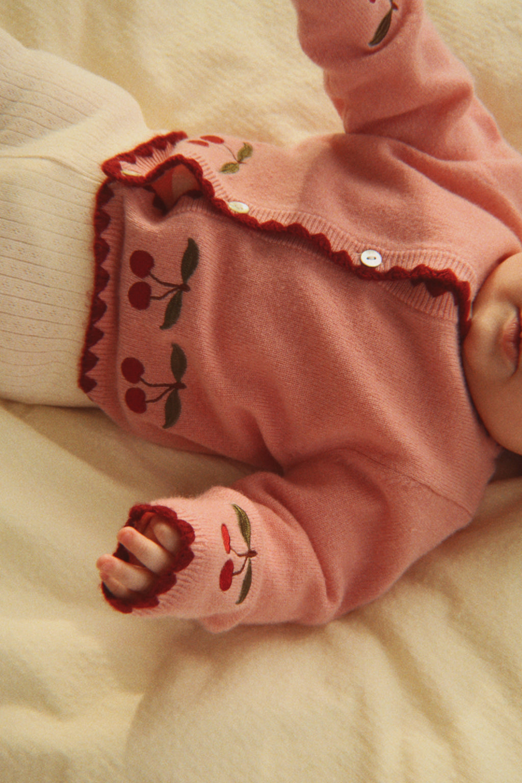 Wollen vest Collette – Pale Blush – Konges Sløjd: detail van de gedragen roze kersentrui met donkere rand.